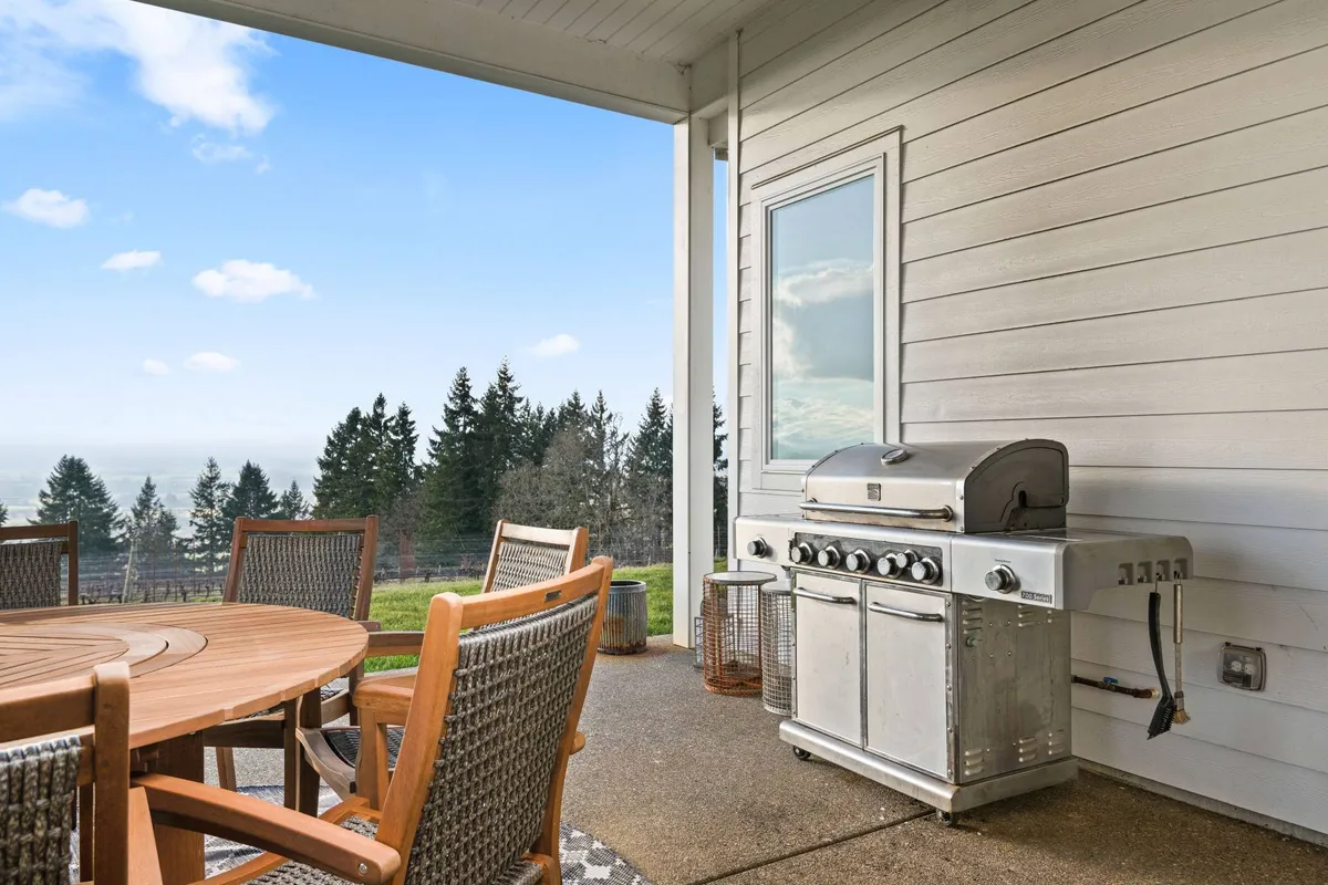 A relaxed outdoor dining area featuring a table, grill, and views of lush trees and landscape. The setting is ideal for al fresco meals, social gatherings, or enjoying a peaceful moment with the stunning natural backdrop.