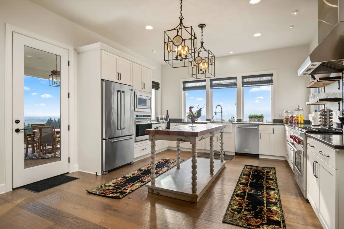 A bright, welcoming kitchen with a large island, stainless steel appliances, and elegant chandelier lighting. Expansive windows provide sunset views over the vineyards, and the layout invites guests to gather, cook, and socialize. The space is both functional and stylish, perfect for wine country entertaining.